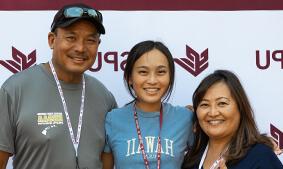 A 好的赌博软件推荐 family including mother, daughter and father in front of an SPU banner.